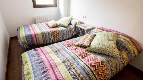 拉普埃夫拉德瓦尔韦尔德Casa Rural Galana的两张带色彩缤纷的毯子和枕头的床