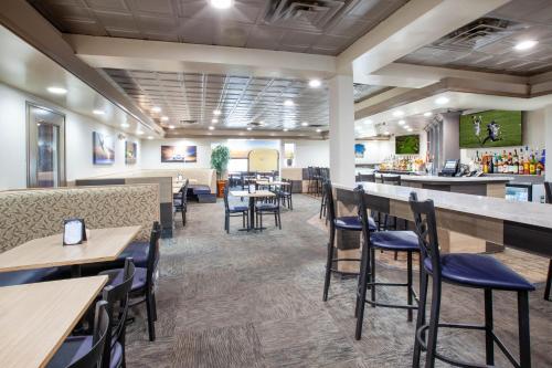 罗缪勒斯Wingate by Wyndham Detroit Metro Airport的一间带桌椅的餐厅和一间酒吧