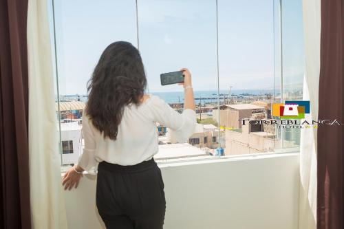 伊洛Torreblanca Hotel的一位从窗户拍摄城市照片的女人