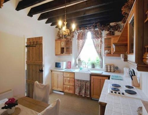 格兰奇奥沃桑茨Inglenook Cottage的一个带桌子和窗户的大厨房