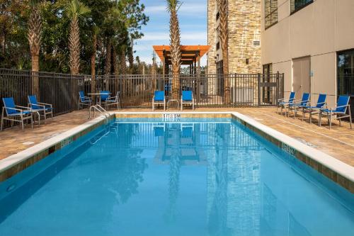 金斯兰Holiday Inn Express & Suites Kingsland I-95-Naval Base Area, an IHG Hotel的一座带蓝色椅子的游泳池和一座建筑