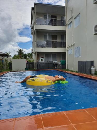 苏瓦FIJI HOME Apartment Hotel的躺在游泳池信息板上的男人