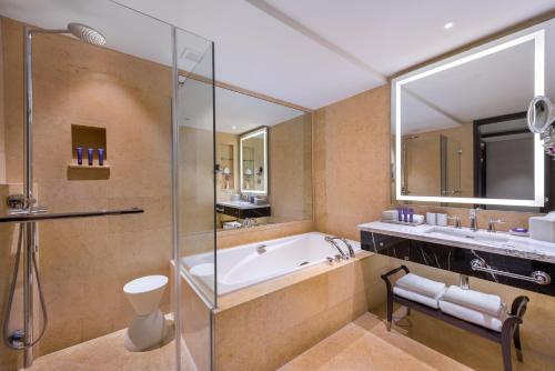 新加坡The Fullerton Hotel Singapore的带浴缸和玻璃淋浴间的浴室。