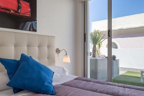 加的斯El Atico del MARQUES free parking by Cadiz4Rentals的一间卧室配有一张带蓝色枕头的床和一扇窗户。