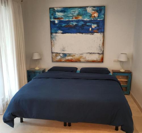 卡萨雷斯Garden Apartment in Finca Cortesin, Altos de Cortesin的卧室配有蓝色的床和墙上的绘画作品