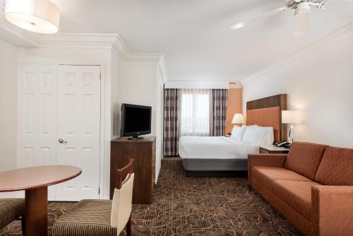 好莱坞劳德代尔堡机场假日酒店的酒店客房配有床、沙发和电视。