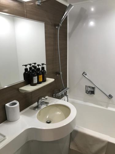Sukumo宿毛爱王经济型酒店的白色的浴室设有水槽和淋浴。