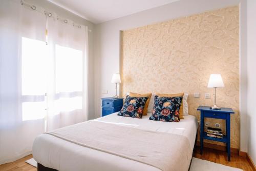 波尔图BBA Apartments Boavista - Casa da Música with Parking的一间卧室配有一张大床和两张蓝色的桌子