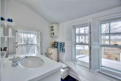费尔菲尔德Gem by the Sound - Beach Front的白色浴室设有水槽和2扇窗户