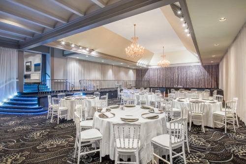 蒙特利尔Armon Plaza Montreal Airpt, Trademark Collection by Wyndham的宴会厅配有白色的桌椅和吊灯