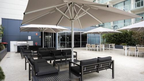 阿德莱德城市附近豪华公寓式酒店的一个带桌椅和遮阳伞的庭院