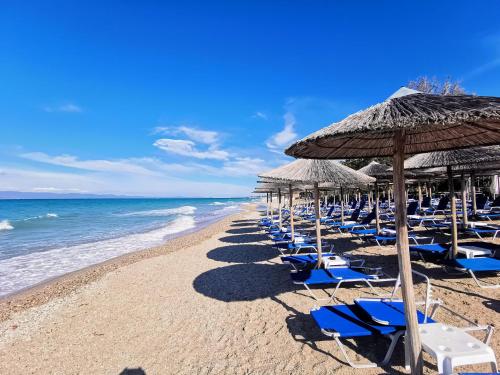 卡尼奥提Purple_Rose_Apartment的海滩上设有椅子和遮阳伞,还有大海