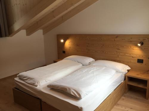 科姆梅扎杜拉MOUNTAIN RESORT Appartamenti的一张铺有白色床单的床和木制床头板