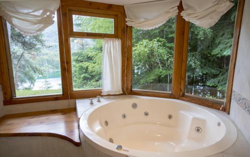 拉安戈斯图拉镇BOG Le Pommier - Cabañas con vista al lago y piscina climatizada的带窗户的客房内的大浴缸