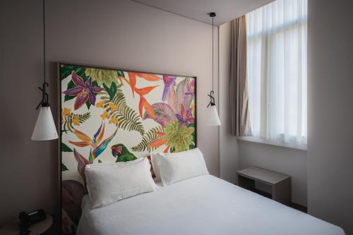 罗马Hotel San Giovanni Roma的卧室配有一张白色床,墙上挂有绘画作品