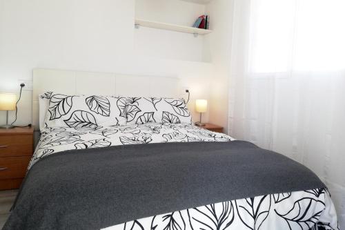 托雷德尔马尔Atico del Mar的一间卧室配有一张带黑白床单和枕头的床。