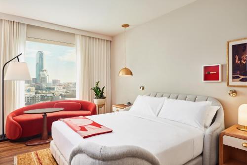 达拉斯Virgin Hotels Dallas的酒店客房,配有一张床和一张红色椅子