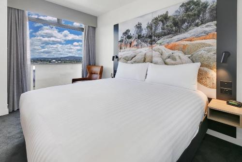 朗塞斯顿廊奇思通美居酒店 的卧室设有一张白色大床和一扇窗户。