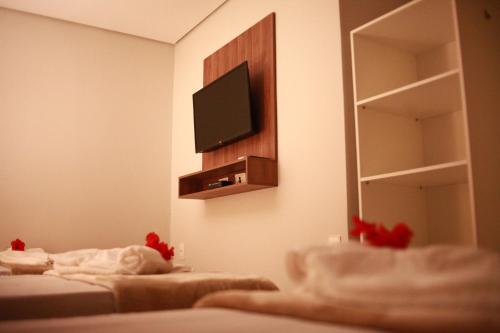 费尔南多 - 迪诺罗尼亚Pousada Aconchego Noronha的一间设有两张床和一台墙上电视的房间