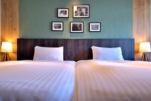 神户科比波特匹亚酒店的卧室内的两张床,墙上有三幅画