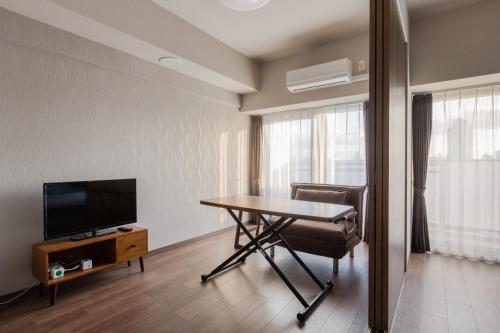 大阪斯选・新大阪酒店公寓的客房设有桌子、电视和桌椅。