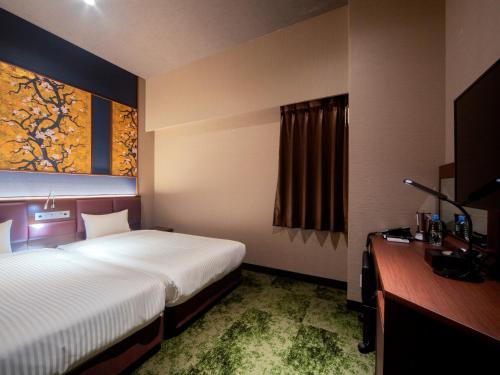 福冈Hotel Halrotto Fukuoka Hakata的酒店客房设有一张大床和一张书桌。