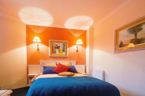 巴比松ARTEMIS SUITE的一间卧室配有一张带蓝色床单和橙色墙壁的床。