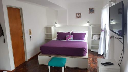 科尔多瓦Luminoso Depto con terraza propia y en la mejor ubicación的一间卧室配有一张紫色的床和一张蓝色的椅子