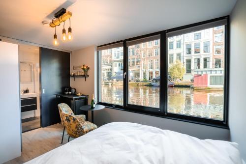 阿姆斯特丹2 Houseboat Suites Amsterdam Prinsengracht的一间卧室设有大窗户,享有运河的景色