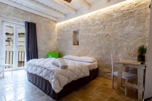 阿尔塔穆拉B&B PIAZZA SAN GIOVANNI - ESSENZE DELLA MURGIA的一间卧室设有一张床和石墙