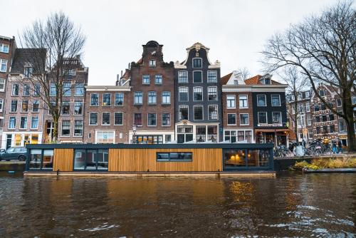 阿姆斯特丹2 Houseboat Suites Amsterdam Prinsengracht的城市河流上的船屋