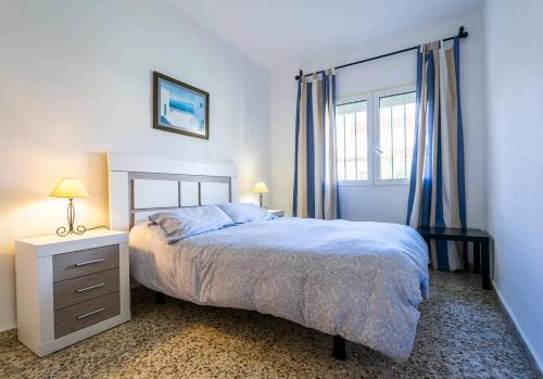 托雷德本纳贾尔邦伊达尔戈太阳海岸度假屋的一间卧室配有床和蓝色窗帘的窗户