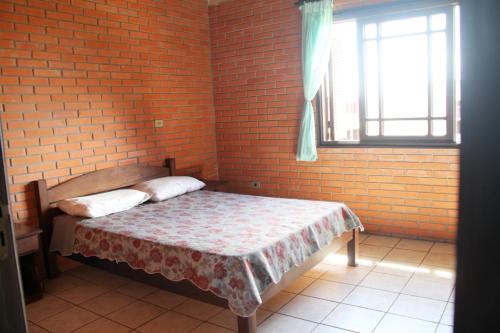 特拉曼达伊Pousada ACM Tramandaí - RS的卧室配有砖墙内的床铺