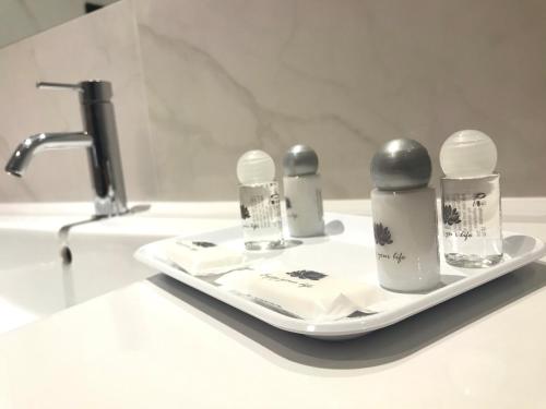 马亚Hotel 3K Porto Aeroporto的浴室柜台上备有四瓶的托盘