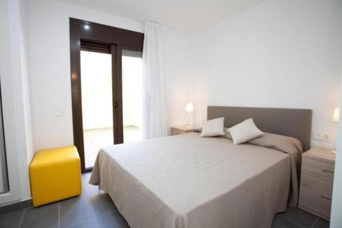 坎布里尔斯Apartamentos Ocea的白色卧室设有一张大床和一张黄色凳子