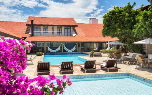 因比图巴因比图巴海滩酒店的一个带游泳池、椅子和紫色鲜花的度假胜地