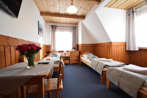 波罗宁Willa Świdrówka 2的一间设有两张床的房间和一张鲜花桌子