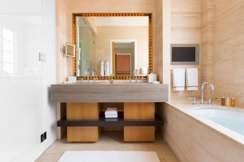 洛杉矶Hotel Bel-Air - Dorchester Collection的一间带水槽和浴缸的浴室以及一台电视。