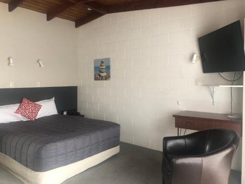  Waipukurau桑顿汽车旅馆的一间卧室配有一张床、一台电视和一把椅子