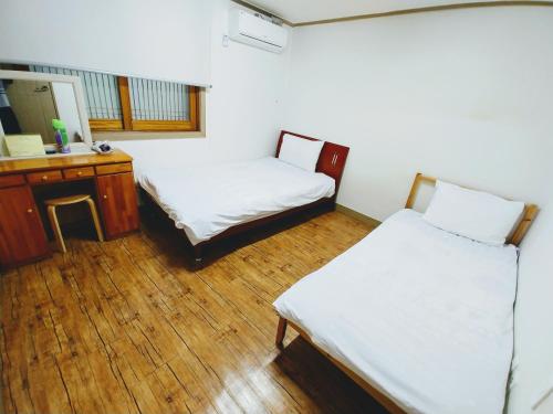 济州市Jeju Masil Guesthouse的客房设有两张床、一张桌子和一面镜子。