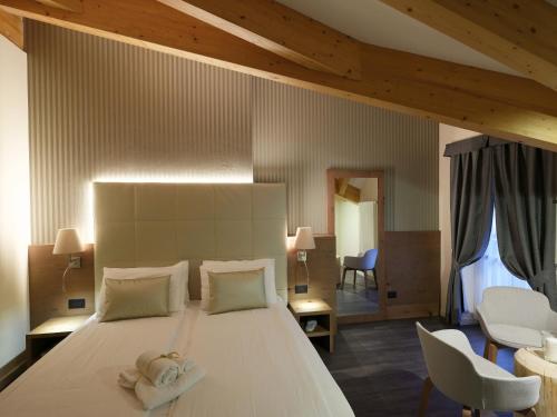 博萨迪法萨X Alp Hotel的卧室配有一张白色大床和两条毛巾