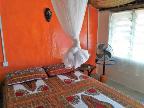 KetaA&Y Wild Camp Ghana的一间卧室配有一张橙色墙壁的床
