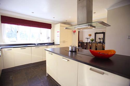 邓巴The Bridge House, Dunbar的厨房配有白色橱柜和柜台上的红色碗