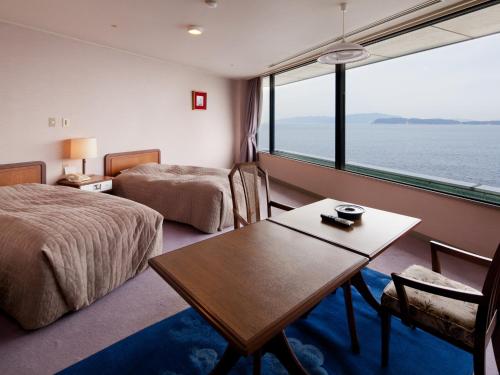 和歌山和歌山加太温泉　加太海月（前东屋五郎海滨酒店）的酒店客房设有两张床、一张桌子和一个窗户。