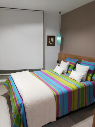 阿维拉The Little House Sir的一间卧室配有一张大床,提供色彩缤纷的床单和枕头