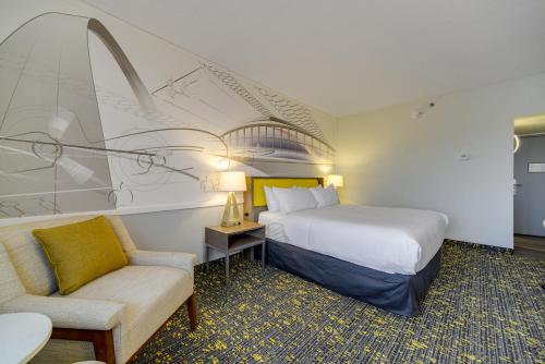 圣路易斯Saint Louis Airport Hotel的配有一张床和一把椅子的酒店客房