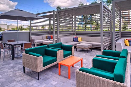 奥兰多Holiday Inn & Suites Orlando - International Dr S, an IHG Hotel的一个带沙发和桌子及遮阳伞的庭院