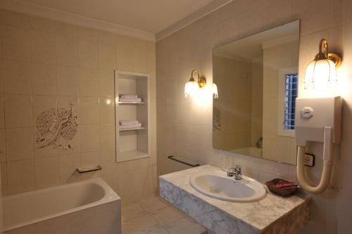 卡佩利亚德斯Hotel Tall de Conill的一间带水槽、浴缸和镜子的浴室