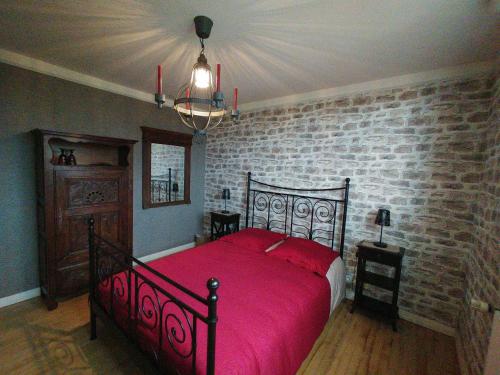 Saint-SauveurLes Chambres de KERCHELGEN的一间卧室设有红色的床和砖墙