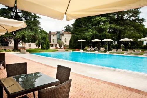 萨韦纳河畔圣拉扎罗瓦菲欧雷黎莱斯别墅酒店的一个带桌椅和遮阳伞的游泳池